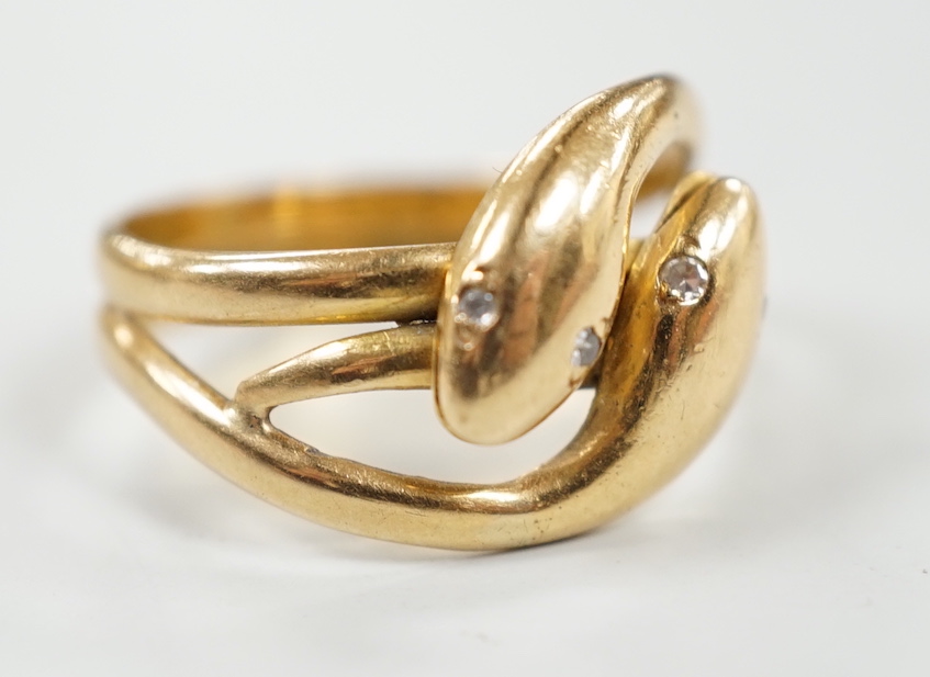 A yellow metal twin shank, two headed entwined serpent ring, with diamond chip set eyes size N/O, gross weight 6.2 grams.